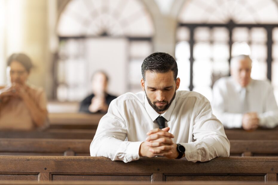 man praying in church pew